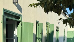 A building with green shutters, a stone pathway, and a table with chairs outside. - Kiti Traditional Residences (Kiti)