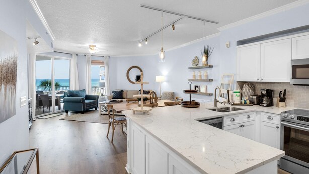 A modern kitchen with white cabinets, a large island, and stainless steel appliances. - Lovely waterfront condo with balcony, pool, hot tub & pickleball (Santa Rosa Beach)