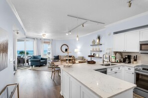 A modern kitchen with white cabinets, a large island, and stainless steel appliances. - Lovely waterfront condo with balcony, pool, hot tub & pickleball (Santa Rosa Beach)