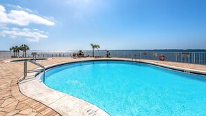 Piscina amb una vista clara de l'oceà, un flotador salvavides i un senyal de perill.