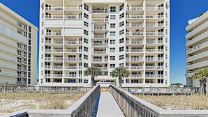 Ein mehrstöckiges Hotel mit Balkonen, einer zentralen Fußgängerzone und Blick auf den Strand.