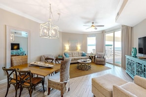 A spacious living area with a dining table, wicker chairs, a sofa, and a ceiling fan. - Amazing views at this renovated 4rth-floor condo with lagoon pool & pickleball (Santa Rosa Beach)