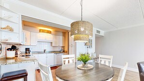 Eine moderne Küche mit weißen Schränken, einer Granit-Arbeitsplatte und einer Hängeleuchte.