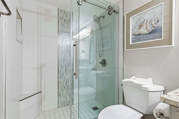 Un bagno moderno con doccia a vetro, servizi igienici e lavabo con piano in marmo.