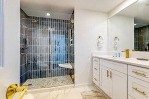 A modern bathroom with a glass-enclosed shower, white cabinetry, and a large mirror. - Gulf-front 3-bedroom condo with balconies off each bedroom & pickleball (Santa Rosa Beach)