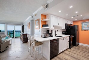 A modern kitchen with white cabinetry, a black refrigerator, and a built-in dishwasher. - Seventh-floor, waterfront condo with views, pool, tennis, & beach access (Fort Walton Beach)