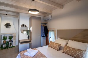 A bedroom with a bed, a mirror, a wardrobe, and a hanging coat rack. - Conaleni - Concona Houses (Rethymno)