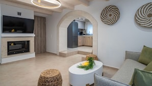 A modern living room with a fireplace, a round coffee table with a candle, and a sofa with cushions. - Conaleni - Concona Houses (Rethymno)