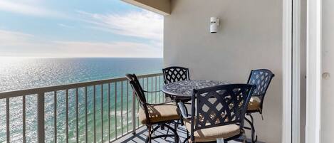A balcony with a table and chairs, overlooking a body of water.