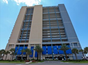 Ein mehrstöckiges Hotel mit zentralem Atrium, einer Tiefgarage und Palmen im Vordergrund.