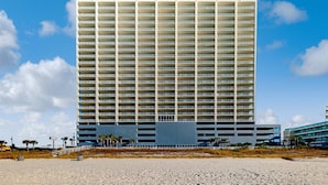 Ein Hochhaus-Hotel mit mehreren Etagen und Balkonen, gelegen in Strandnähe bei blauem Himmel.