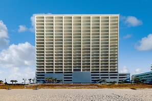 A high-rise hotel with multiple floors and balconies, located near a beach with a clear sky. - Top-floor penthouse condo with amazing view, balcony, W/D, pools, gym, & hot tub (Panama City Beach)