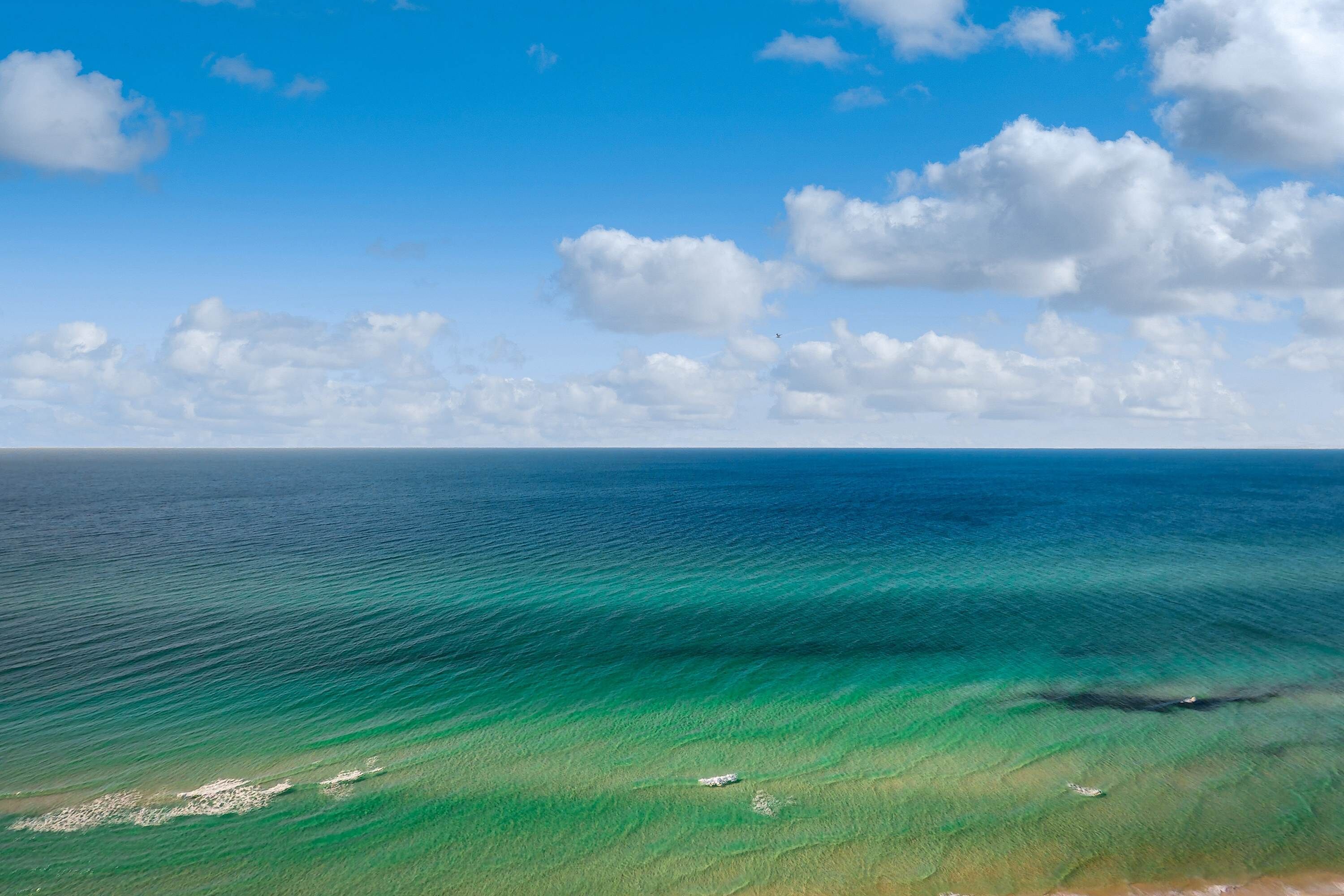 Un paysage côtier avec une eau d’un bleu limpide et une plage de sable.