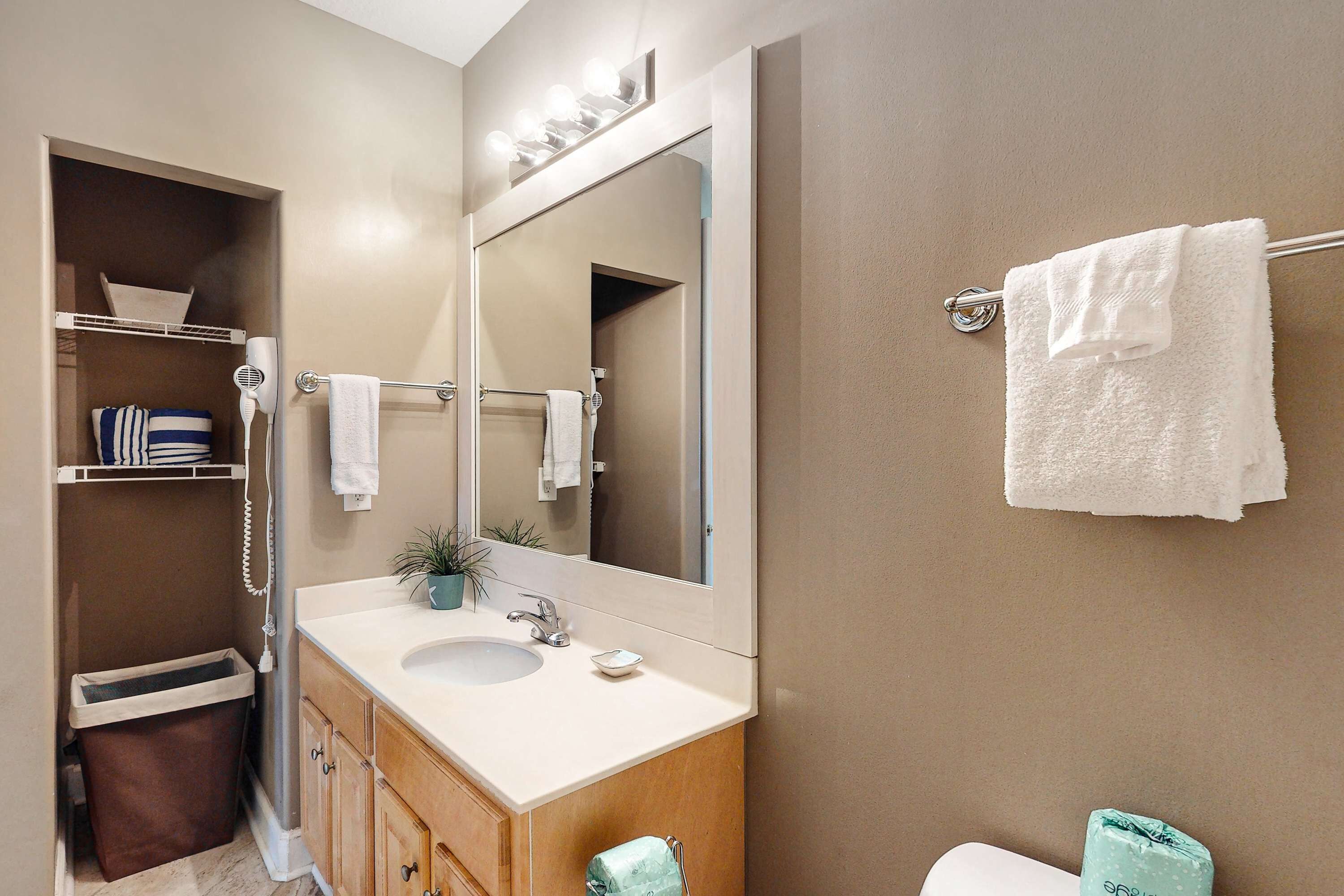 Une salle de bain équipée d’un lavabo, d’un miroir, d’un porte-serviettes et d’une petite étagère contenant des articles de toilette.