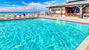 Une piscine d’un bleu éclatant, dotée de chaises longues et d’un espace bar.