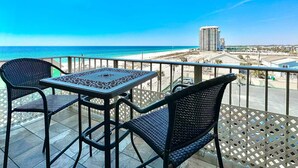 Un balcon avec une table et des chaises, donnant sur une plage et offrant une vue sur la ville.