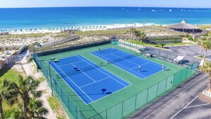 Una cancha de tenis al lado de una playa, con vista al océano.