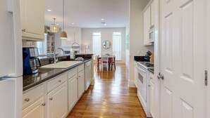 Una cocina moderna con armarios blancos, suelo de madera e iluminación colgante.