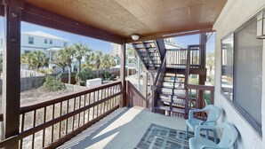 A covered outdoor area with a wooden railing, a staircase, and two plastic chairs. - Peaceful studio beach condo with shared pool & full W/D (Panama City Beach)