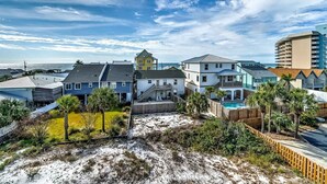 A coastal residential area with houses, a wooden fence, and a sandy beach. - Peaceful studio beach condo with shared pool & full W/D (Panama City Beach)