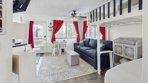 A compact living space with a sofa, a small table, a ceiling fan, and a white cabinet. - Peaceful studio beach condo with shared pool & full W/D (Panama City Beach)