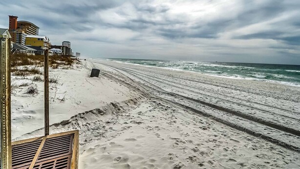 A beach with a sandy shore and waves. There are buildings and a metal structure on the left. - Peaceful studio beach condo with shared pool & full W/D (Panama City Beach)