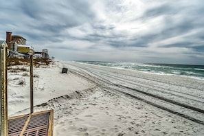 A beach with a sandy shore and waves. There are buildings and a metal structure on the left. - Peaceful studio beach condo with shared pool & full W/D (Panama City Beach)