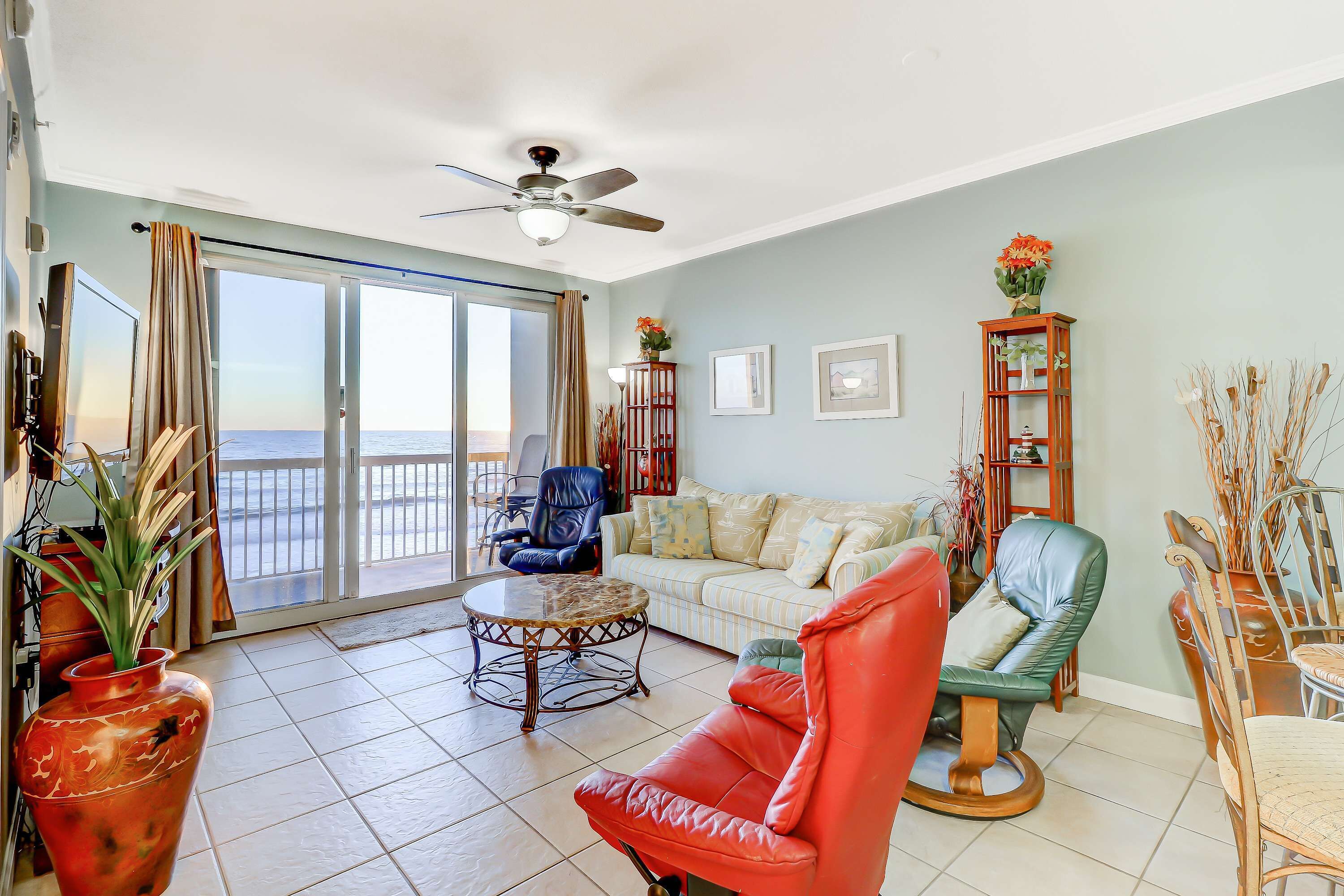 Un salon comprenant un canapé, des fauteuils, une table basse et offrant une vue sur la mer grâce à de grandes portes vitrées.