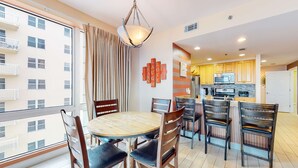 Un apartamento moderno con comedor, cocina y ventanas amplias.