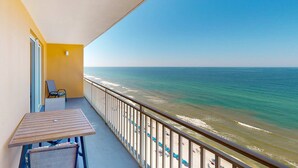 A balcony with a view of the ocean, a table, and a chair. - Gulf-front condo with pool, hot tub, balcony, & complimentary beach service (Panama City Beach)