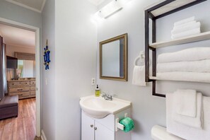 Un bagno con un lavandino bianco, uno specchio e un porta asciugamani.