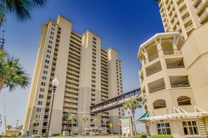 Un hotel moderno de gran altura con varios balcones y un puente peatonal.