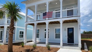 Une maison à deux étages avec un balcon, une porte d’entrée et un drapeau américain.