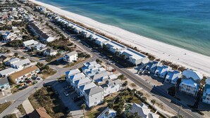 Uma área residencial costeira com casas à beira-mar, céu claro e vista para o oceano.