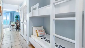Ein Zimmer mit Etagenbetten, einem Essbereich mit Tisch und Stühlen und Blick ins Freie.