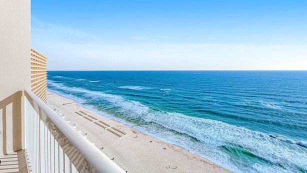 Blick auf einen Strand vom Balkon, der Himmel ist wolkenlos.