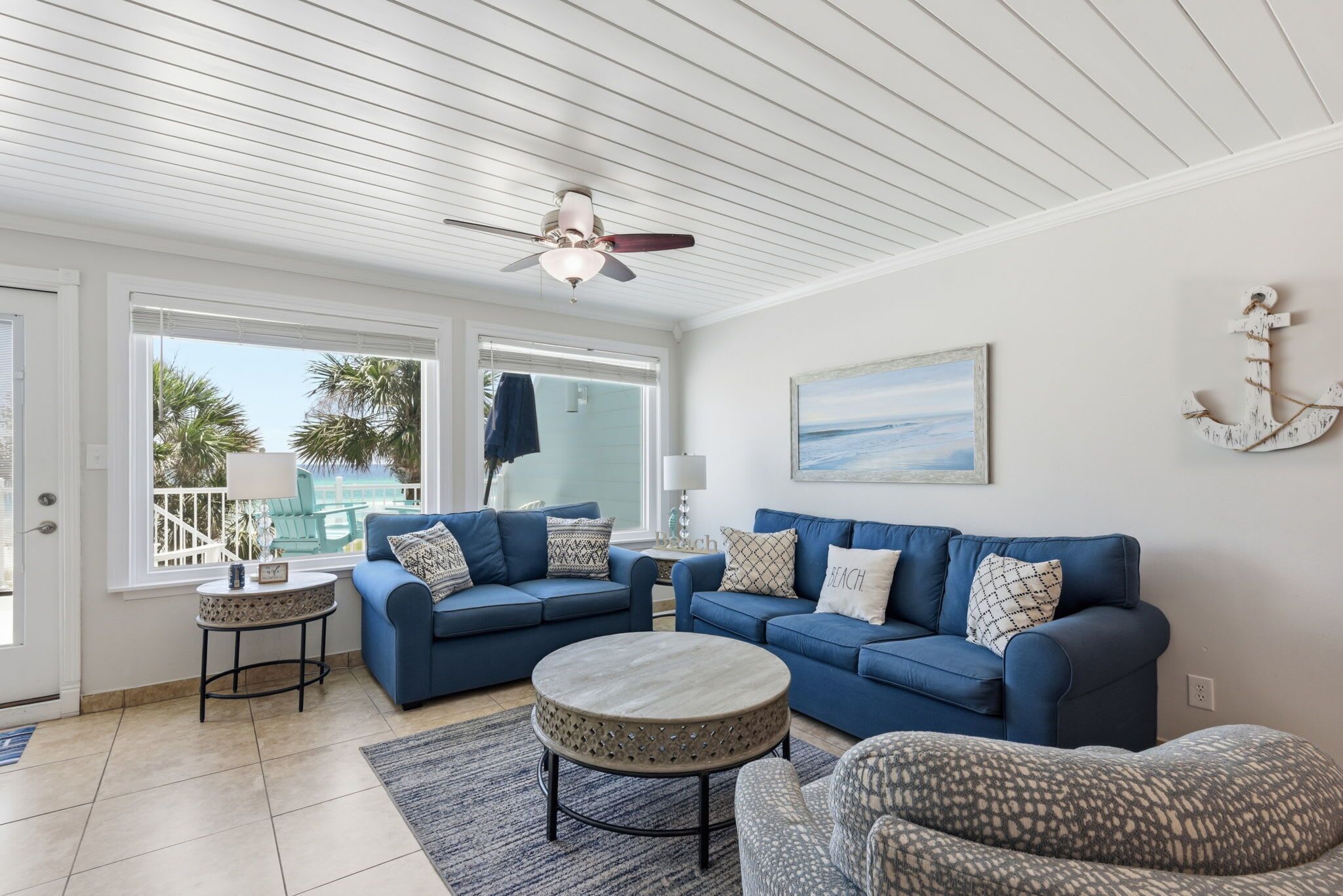 A living room with a blue sofa set, a round coffee table, and a ceiling fan.