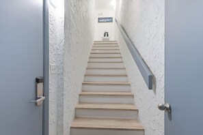 A staircase with white walls and a sign that reads 'happy place' at the top. - Beachfront Townhouse w/ Modern Upgrades Shared Pool, Fast WiFi, Outdoor Shower (Panama City Beach)