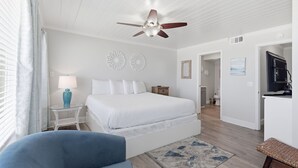 A bedroom with a bed, a ceiling fan, a nightstand, a lamp, and a TV. - Beachfront Townhouse w/ Modern Upgrades Shared Pool, Fast WiFi, Outdoor Shower (Panama City Beach)