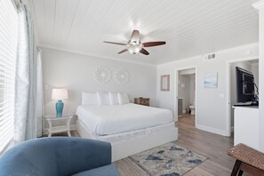 A bedroom with a bed, a ceiling fan, a nightstand, a lamp, and a TV. - Beachfront Townhouse w/ Modern Upgrades Shared Pool, Fast WiFi, Outdoor Shower (Panama City Beach)