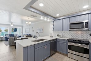 A modern kitchen with grey cabinets, stainless steel appliances, and a herringbone tile backsplash. - Beachfront Townhouse w/ Modern Upgrades Shared Pool, Fast WiFi, Outdoor Shower (Panama City Beach)