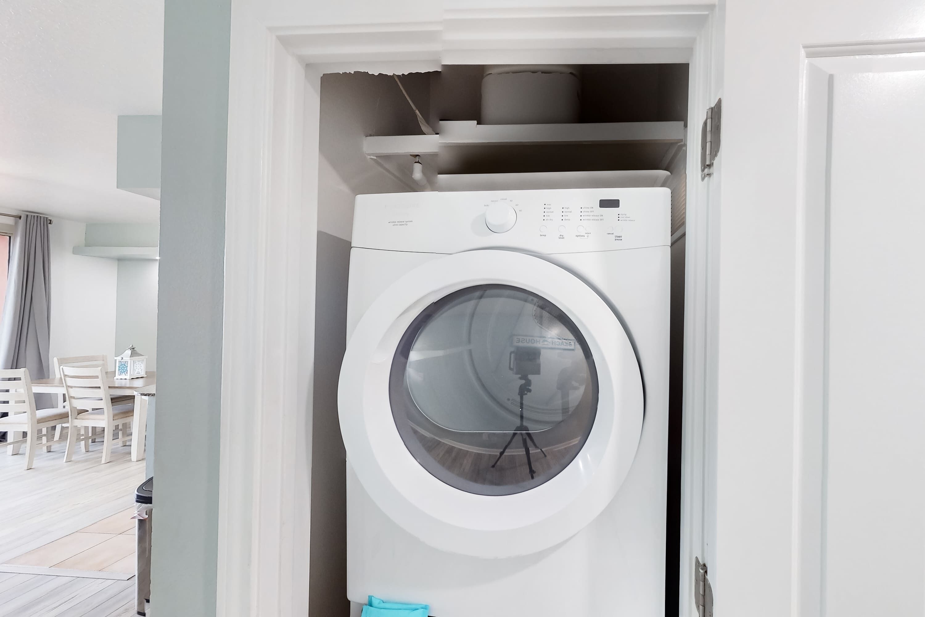 Lavadora blanca compacta en un lavadero pequeño, con un picaporte visible y un interruptor de luz arriba.