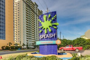 Un edificio con un letrero que dice 'SPLASH PARKING' y una camioneta roja estacionada adelante.
