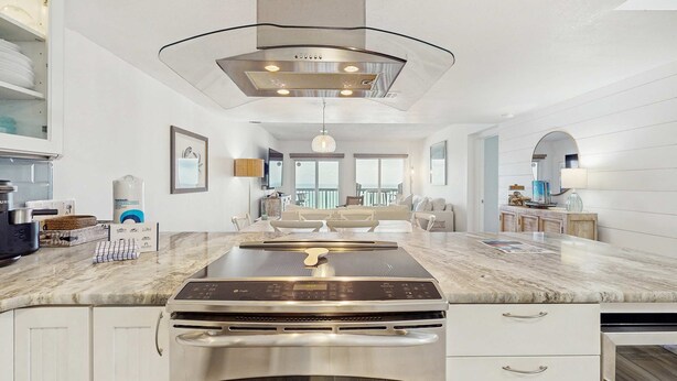 Une cuisine moderne dotée d’un grand îlot central, d’appareils électroménagers en acier inoxydable et d’un luminaire suspendu au design contemporain.