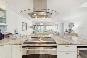 A modern kitchen with a large island, stainless steel appliances, and a contemporary pendant light.