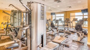 Een sportschool met diverse fitnessapparaten, waaronder loopbanden en krachtapparaten, in een ruime opstelling.