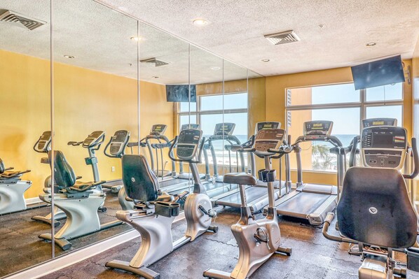 A gym with various exercise machines, large windows, and a mirror wall. - 14th-floor oceanfront condo with Gulf views, outdoor pool, balcony, W/D, & AC (Panama City Beach)