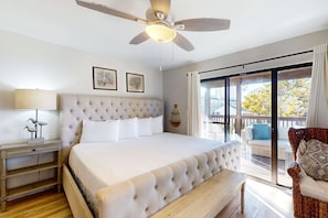 A bedroom with a large bed, a ceiling fan, a nightstand, and a view of the outdoors through a sliding glass door. - Renovated Townhome with Central AC, Shared Pools & Hot Tubs–Minutes to Beach (Panama City Beach)