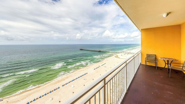 A balcony with a view of a beach and a pier.