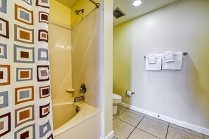 Une salle de bain avec une baignoire, des toilettes et des serviettes rangées sur un porte-serviettes.